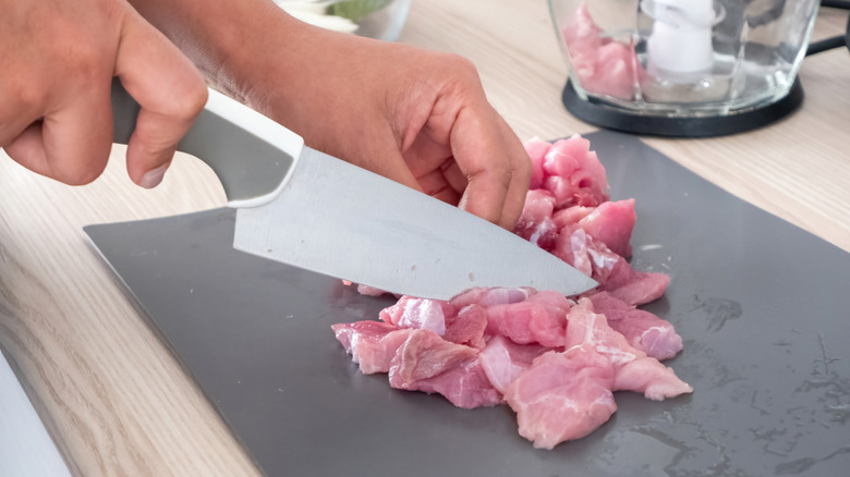 Kesme tahtasında çiğ et kesen kişinin yakın çekimi