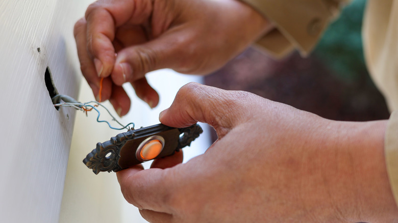 Eski bir kapı zilinde kabloları tutan kişinin elleri