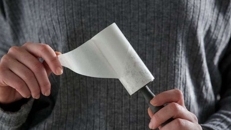 Tüylü bir tiftik silindirini tutan ve şeridi çıkaran el