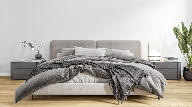 gri kumaşın çeşitli tonlarında yatak ve iki gri komodin bulunan lüks yatak odası