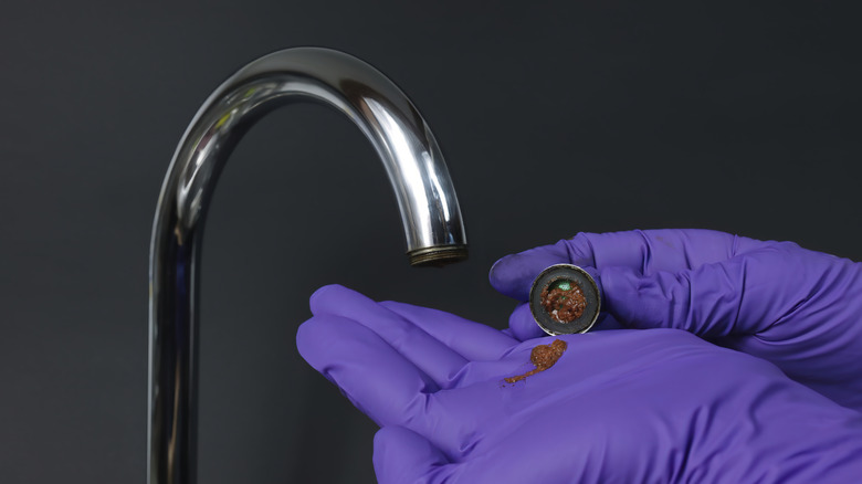 Musluk Havalandırıcısını temizleyen bir kişi