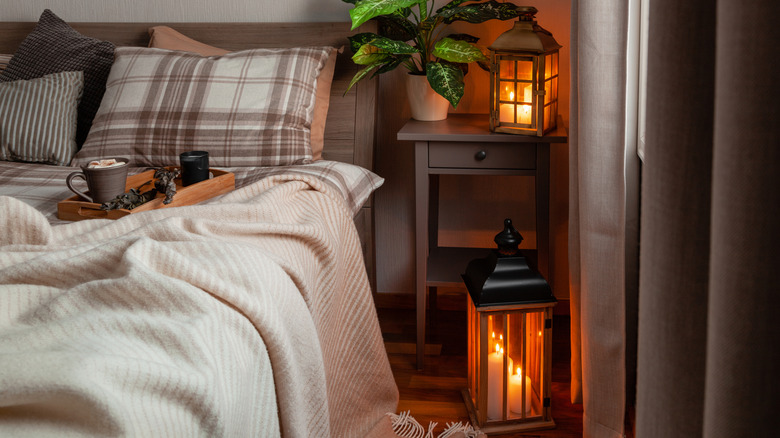 Yumuşak mum ışıkları, rahat battaniyeler ve üzerinde içecek bulunan tepsiyle rahat yatak odası.