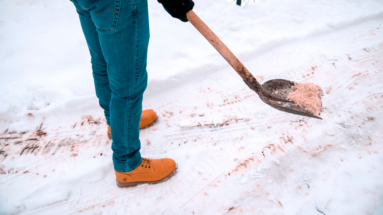 Kar üzerine kürekle eriyen turuncu buz yayan kişi