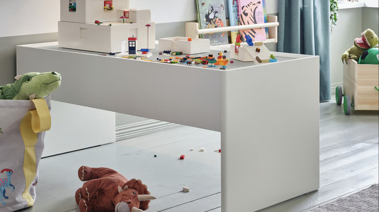 Oyun odasında yapı taşlarıyla kaplı, geniş saklama çekmeceli IKEA DUNDRA etkinlik masası