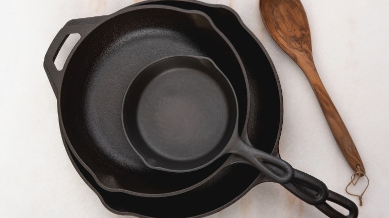 Tahta kaşığın yanında temiz terbiyeli dökme demir tava yığını