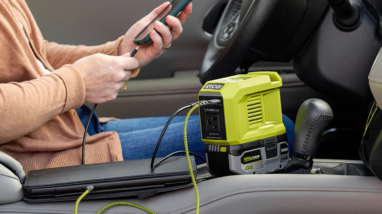 Arabasında 18V ONE+ Güç Kaynağı ile telefonunu şarj eden kadın