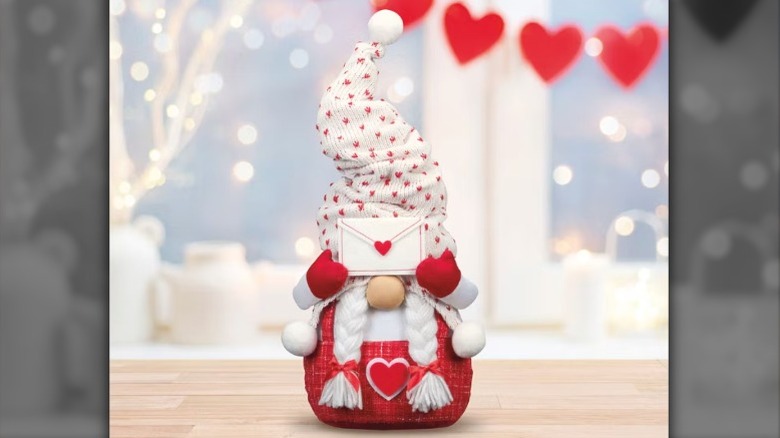 Sivri şapkalı içi doldurulmuş bir cüce, gözlerinin üzerinde bir mektup tutuyor