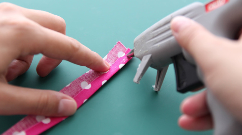 Kumaş süslemesini yapıştırmak için iki el çalışıyor.