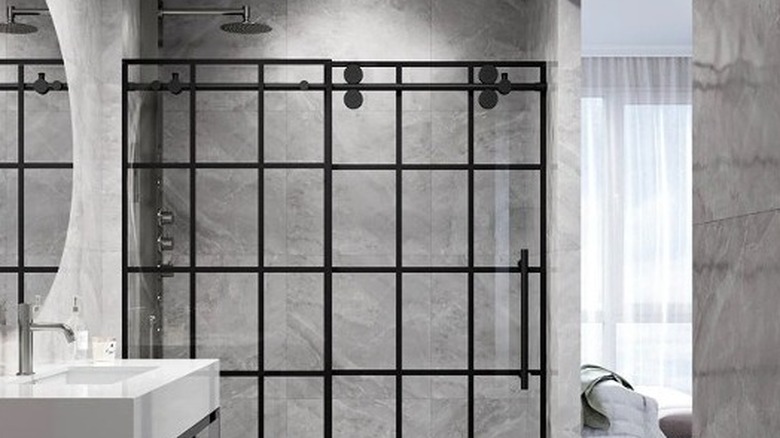 Üst kısmında tekerlekler bulunan gümüş ray üzerine monte edilmiş çerçevesiz sürgülü cam kapılı, beyaz metro fayanslı banyo