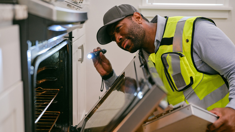 Müfettiş mutfak aletlerini kontrol ediyor, fırına bakıyor