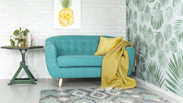 Botanik duvar kağıdı ve geometrik desenli kilim bulunan oturma odası