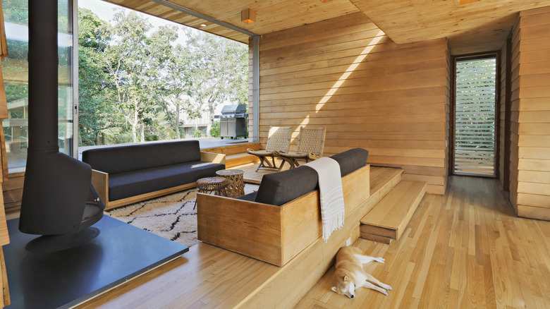 Birbirine bakan kanepeler, kilimler ve şömineyle batık bir çukur hissi veren modern ev