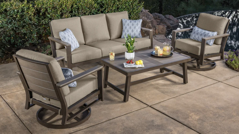 İki sandalye, bir kanepe ve bir masadan oluşan bej ve kahverengi veranda seti
