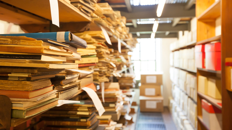 İkinci el bir mağazanın raflarında üst üste yığılmış eski kağıtlar, dosyalar ve belgeler.