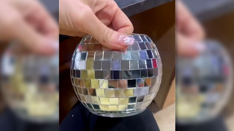 Balık kasesinden yapılmış aynalı bir disko vazosu tutan el