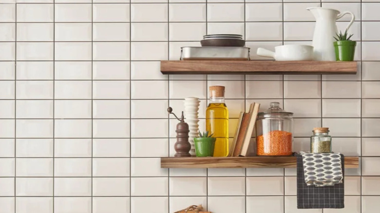 Beyaz fayanslı bir duvarda akasya ağacından yapılmış yüzen raflar.