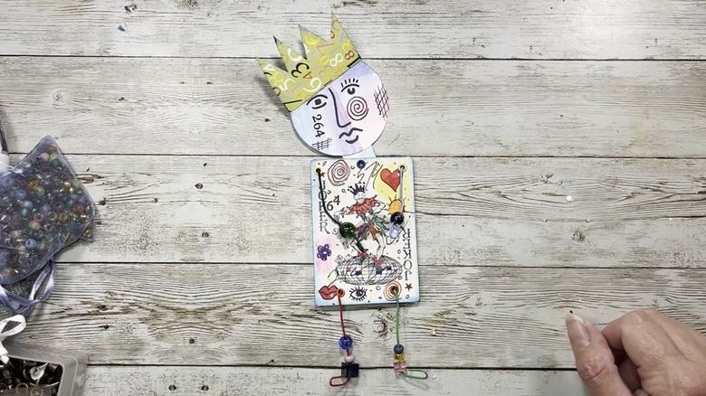 Ahşap arka plan üzerinde joker kartı, tel ve boncuklardan yapılmış karakter