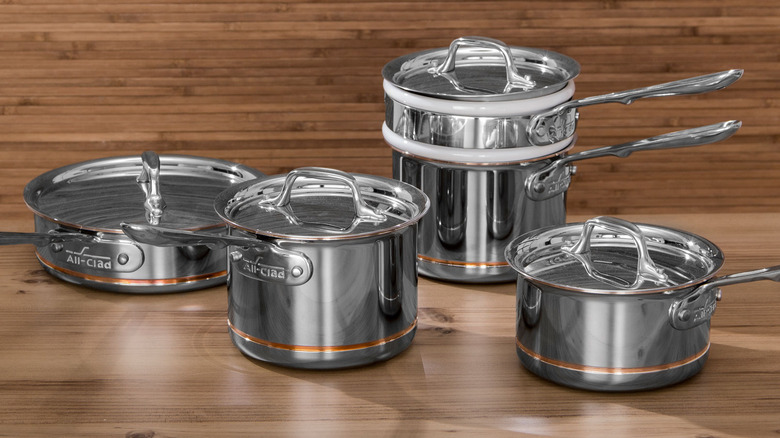 Ahşap panelli bir odada çeşitli Tamamen Kaplamalı bakır çekirdekli tencere ve tavalar