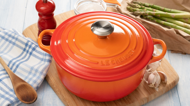 Kesme tahtası üzerinde turuncu ve kırmızı ombre Le Creuset Dutch fırın.