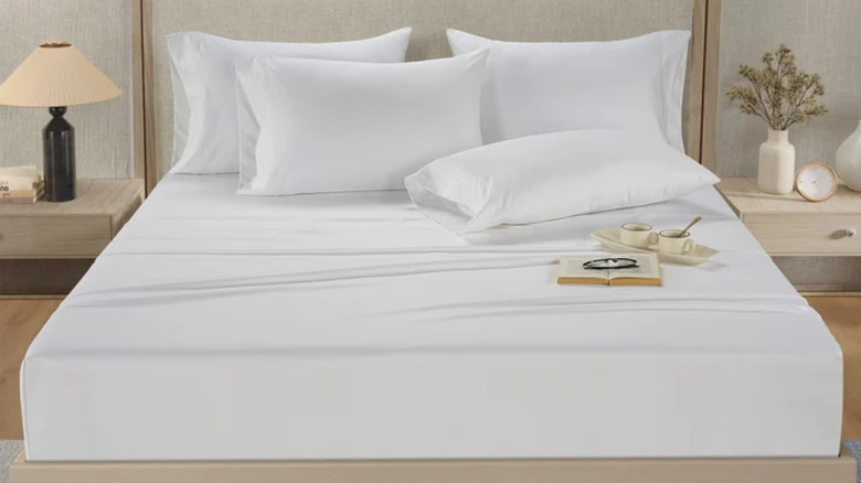 Kabarık yastıklar ve iki fincan çay ile konforlu beyaz bir yatak.