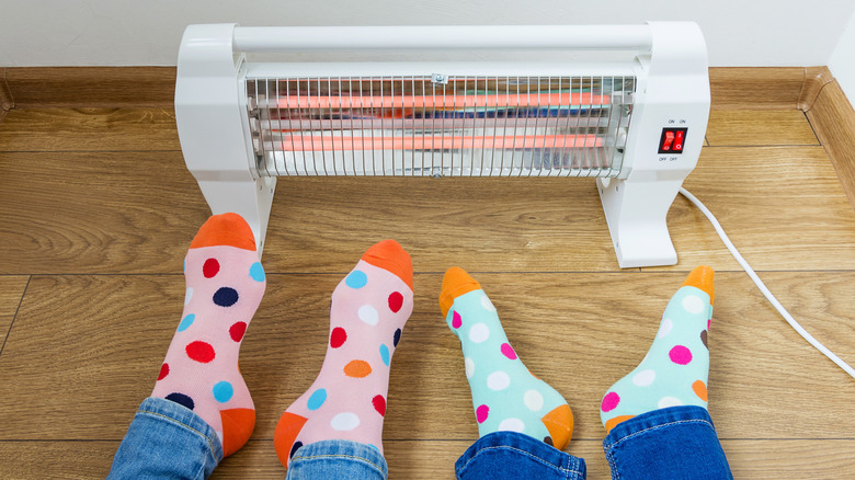 Elektrikli ısıtıcının yanında ayaklar ısınıyor