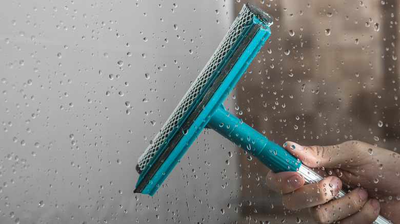 Cam ekim makinesini silecekle temizleyen kişi.