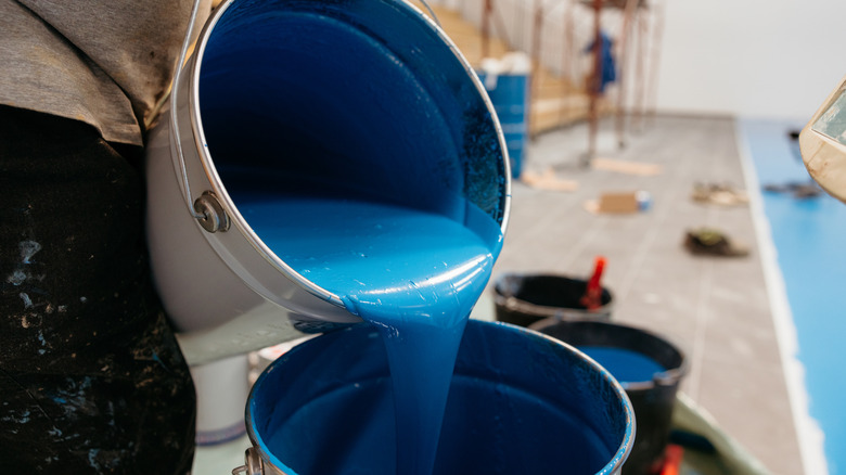 Epoksi boyayı bir kutudan diğerine döken bir kişi