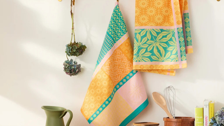 Mutfakta, tezgahın üzerinde duran yemek kitaplarının ve pişirme aletlerinin üzerinde iki renkli el havlusu asılı.