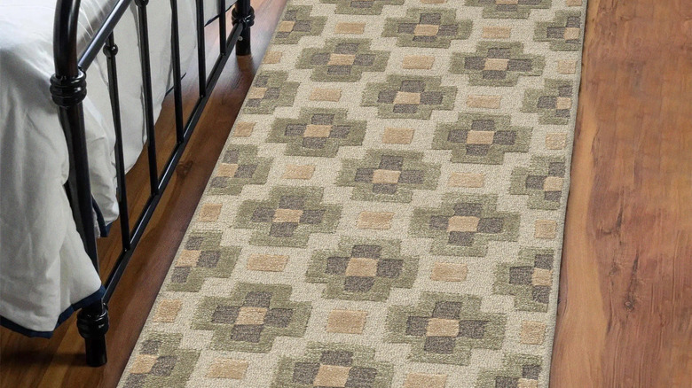 Yatağın yanında parke zemin üzerinde toprak tonlarında geometrik tasarıma sahip yolluk şeklinde bir halı bulunmaktadır.