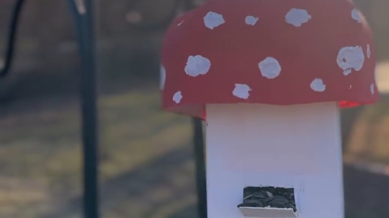 Bahçedeki bir direğe asılı mantar şeklinde ileri dönüştürülmüş süt kabı kuş besleyici