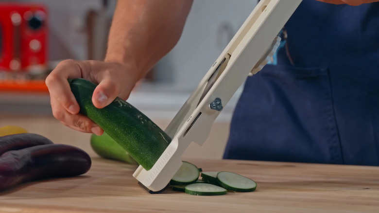 Salatalığı mandolinle dilimleyen adam