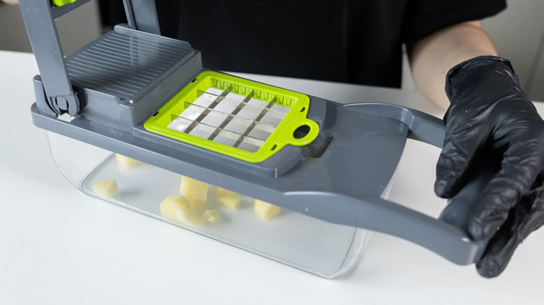 Eldivenli eller manuel sebze dilimleyiciyi tutuyor