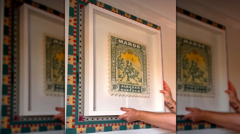 Bir sanat eserinin etrafındaki duvara renkli bir geometrik çerçeve boyanmıştır.