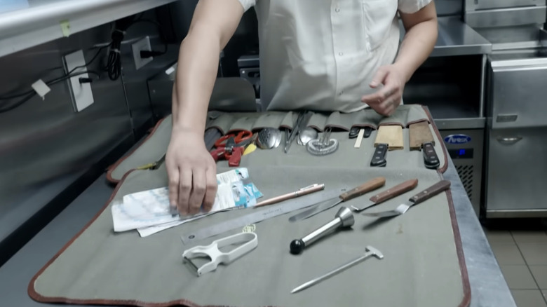 Bir şefin elinde bıçak rulosu var.