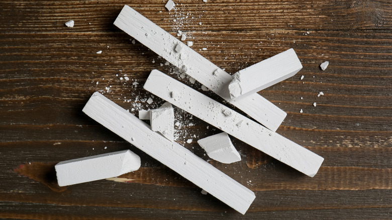 Ahşap bir masanın üzerinde bütün ve kırık tebeşir parçaları.