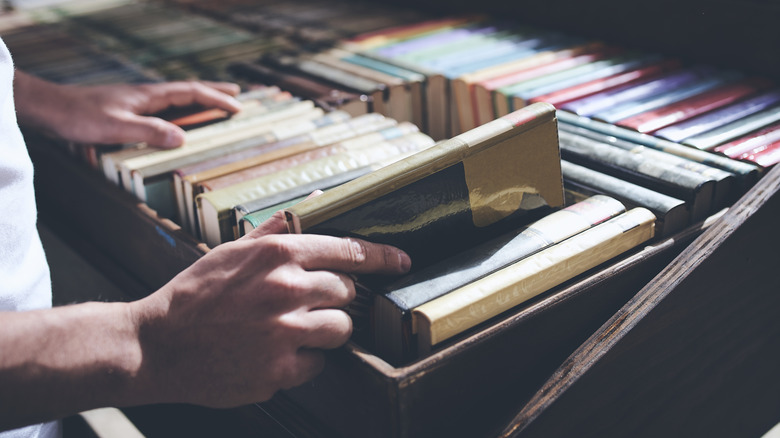 İkinci el mağazasının çöp kutusundan kitap seçen adam