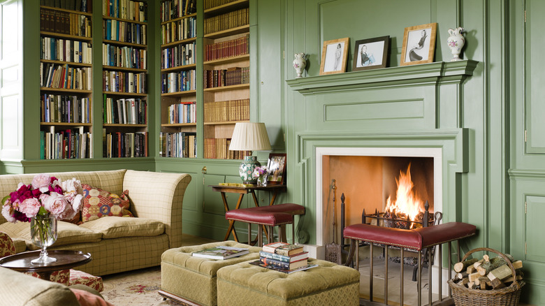 Süslü bir şömineye sahip zeytin yeşili bir kütüphane