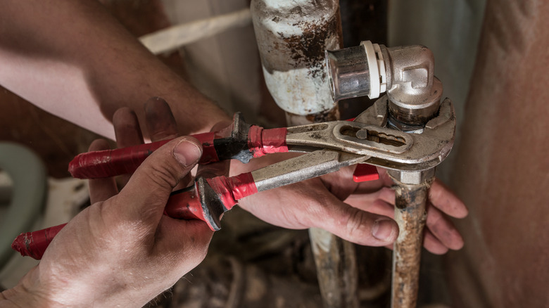 Eski bir evin boruları üzerinde çalışan tesisatçı