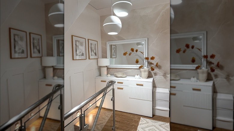 Ayna, pembe mermer duvar kağıdı ve beyaz dekora sahip modern bir oda