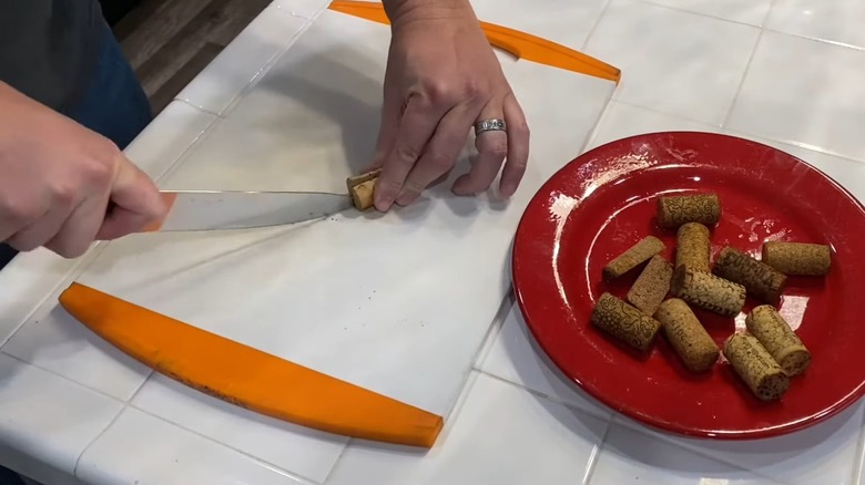 Doğrama tahtasında şarap mantarlarını kesen adam