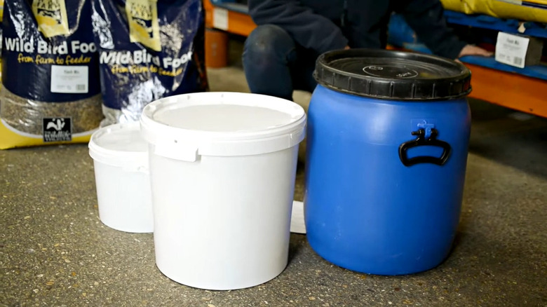 Kuş tohumlarını depolamak için kullanılan ağır hizmet tipi plastik kovaların, kuş tohumu torbalarının yanında görünümü