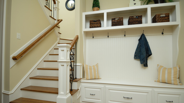 Kancaları, bölmeleri, çekmeceleri ve merdivenin yanında bir bankı olan salon ağacı.