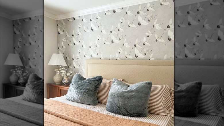 Vurgulu duvar olarak gri ve beyaz, vinç temalı duvar kağıdına sahip bir yatak odası.