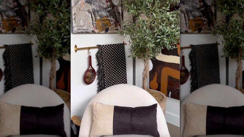 Oturma odası duvarına asılı IKEA rayı, üzerinde battaniye ve dekor asılıydı.