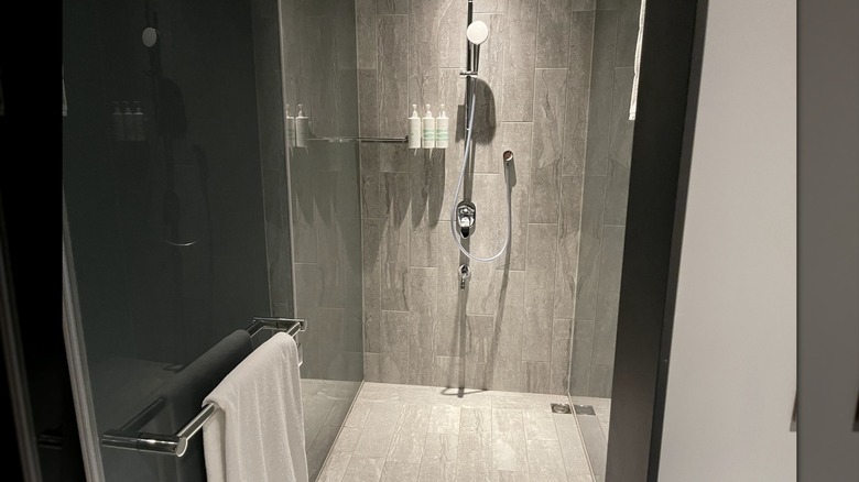 Taş fayanslı bir duş ve kapıya asılı bir havlu