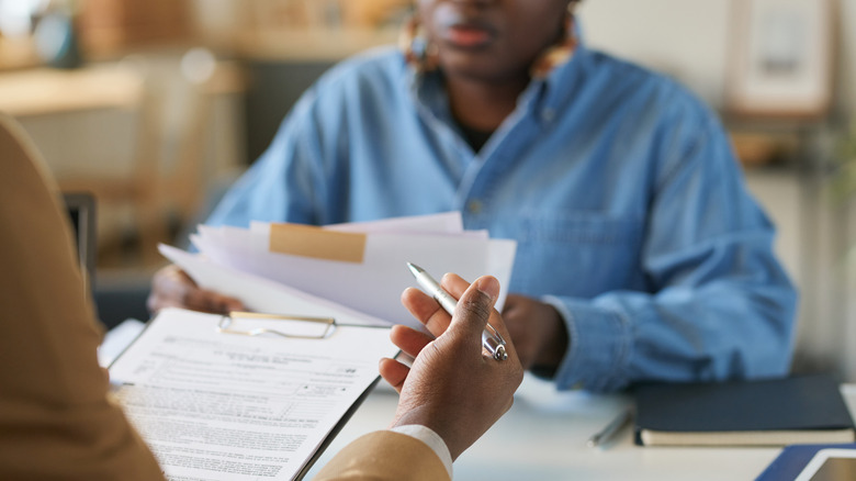 Karşılıklı oturan ve yasal belgeleri inceleyen iki kişi