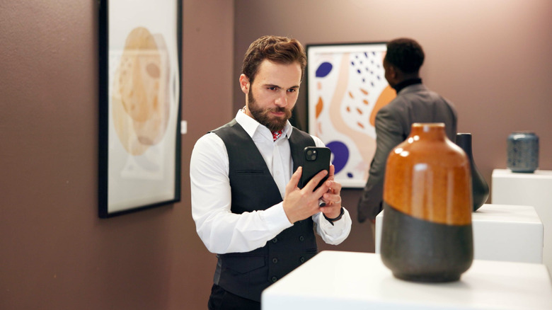 galeride sanatın fotoğrafını çeken adam