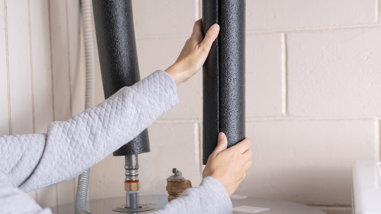 su ısıtıcı borularına yalıtım ekleyen kişi