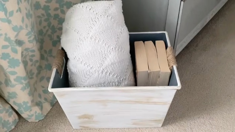 Dolar Ağacı soyunma kutusu, battaniye ve kitapları saklamak için dekoratif beyaz bir saklama kabına dönüştü.