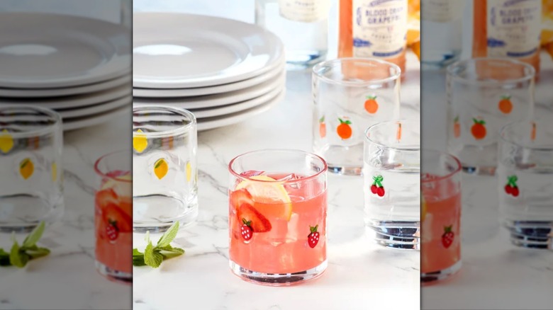 Masanın üzerinde oturan dört meyve ikonu bardağından oluşan set.